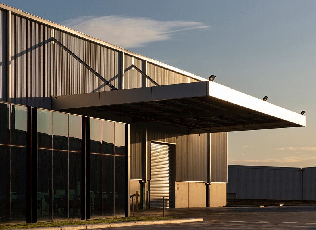 Business Insurance - Exterior View of a Modern Industrial Office Building at Sunset with Metal Siding and Large Front Windows